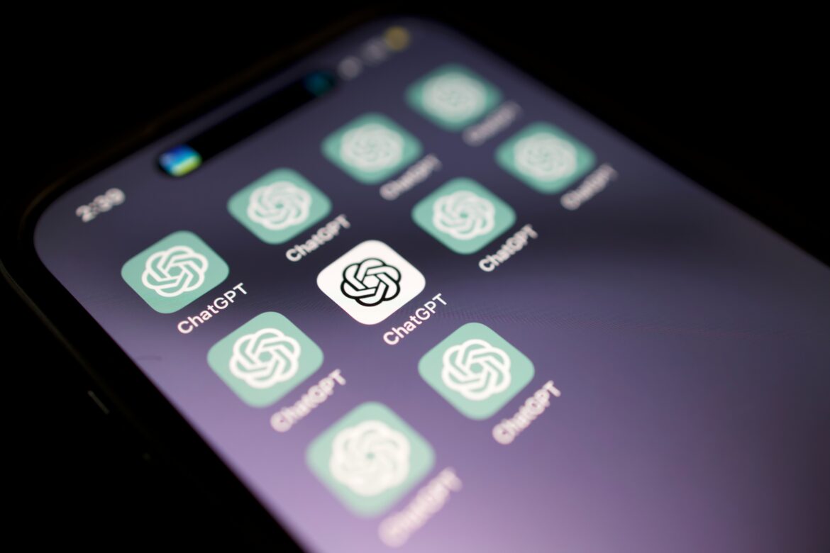 A smartphone screen displays multiple ChatGPT app icons, each with the OpenAI logo on a green background, arranged in a grid. The screen is slightly tilted and appears in low light.